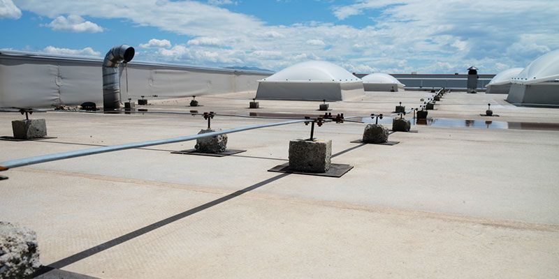 Flat rooftop with vents, pipes, and white domed structures under a clear sky