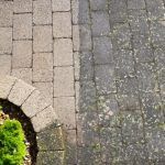 Stone pavers beside a curved brick border and a patch of grass, next to cracked gray pavement