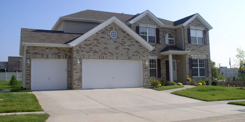 Suburban two-story stone house with a three-car garage and a concrete driveway