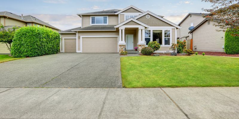 Suburban two-story house with a wide driveway, garage, and neatly kept front lawn.