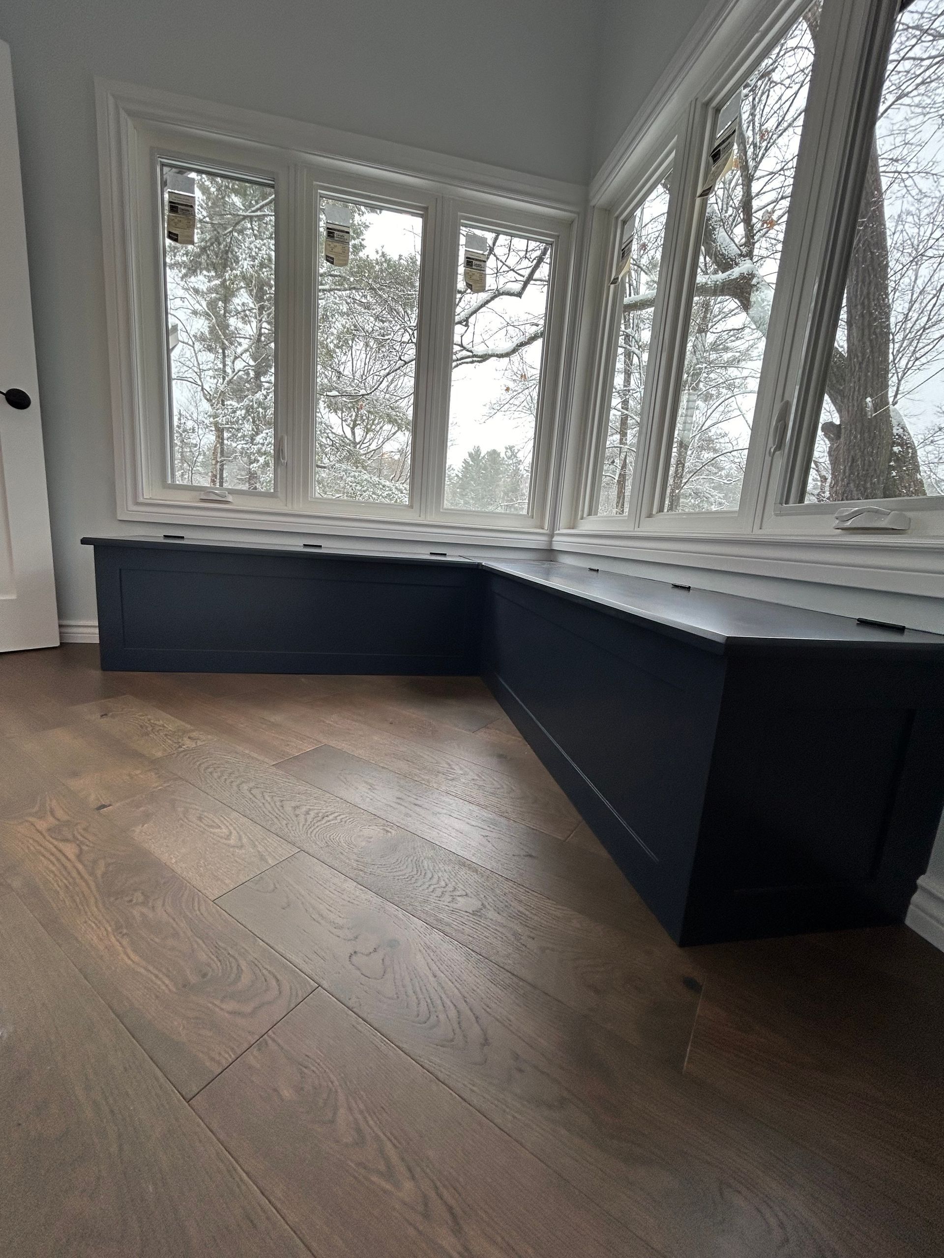 Dark blue built-in bench under a white-framed window. Wooden floor.