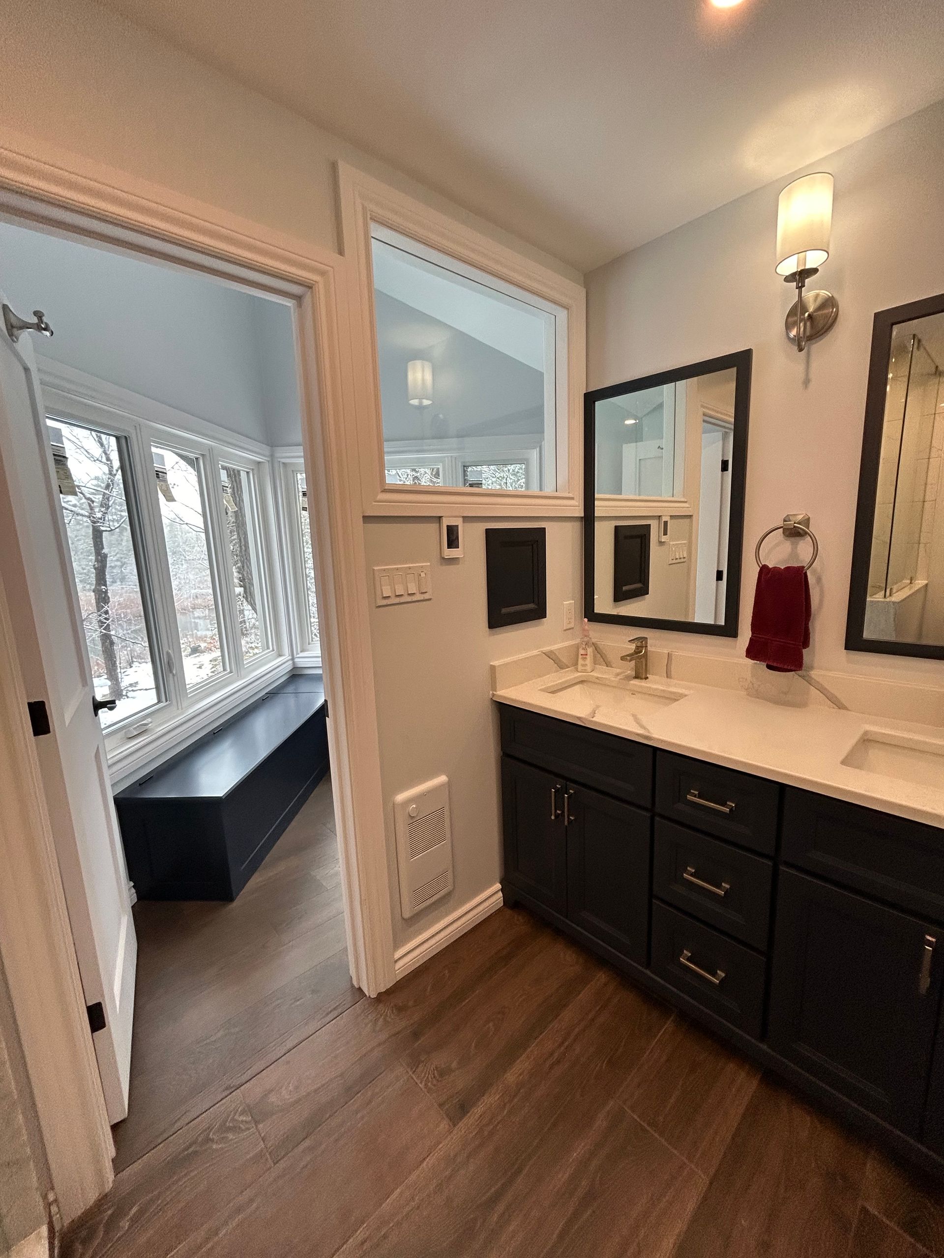 Bathroom with dark cabinets, light countertops, and a window seat with a view.