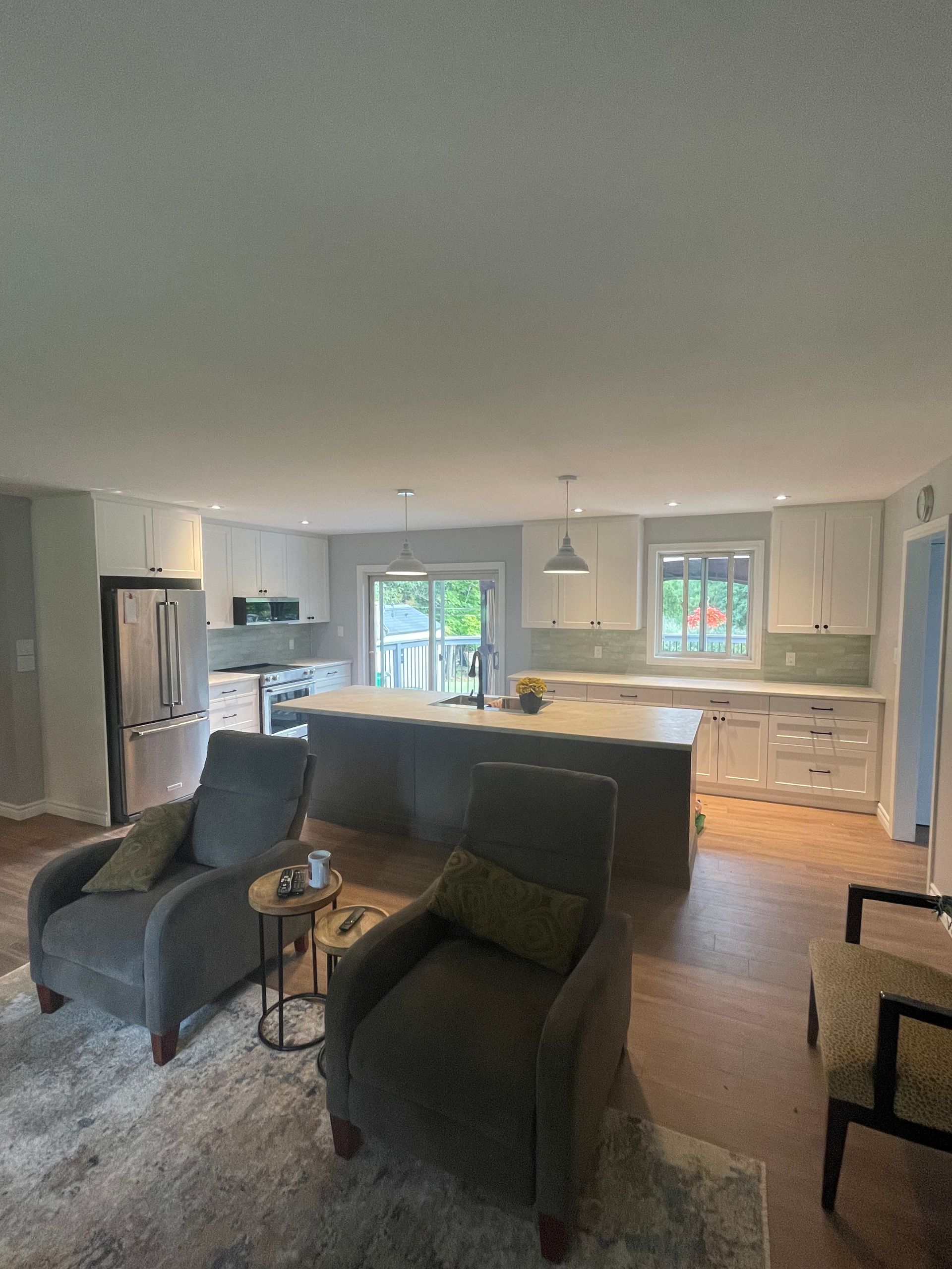 Open-concept kitchen and living area with a large island, two armchairs, and wood floors.
