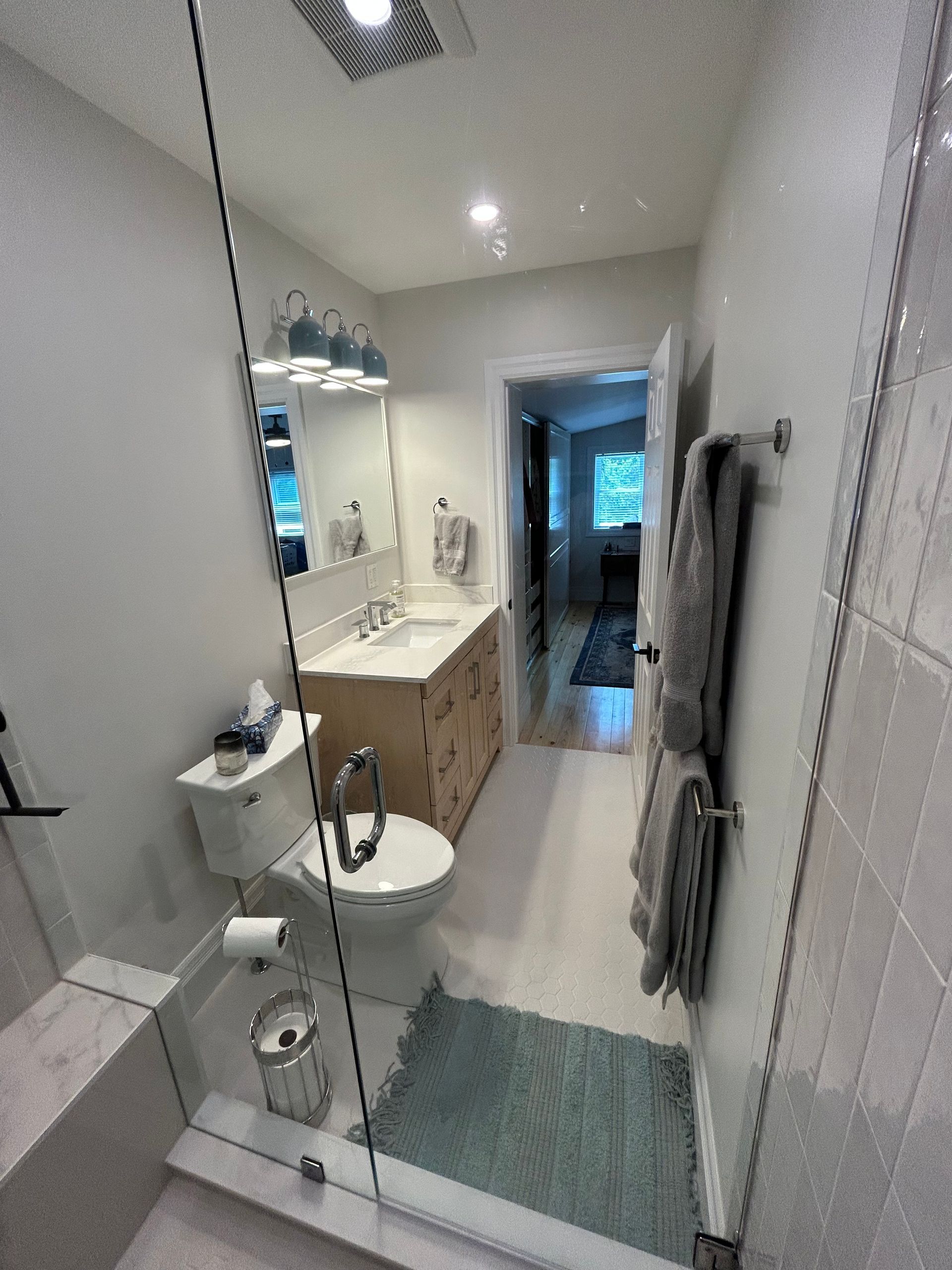 Bathroom with white walls, a wood vanity, and a shower with glass doors.