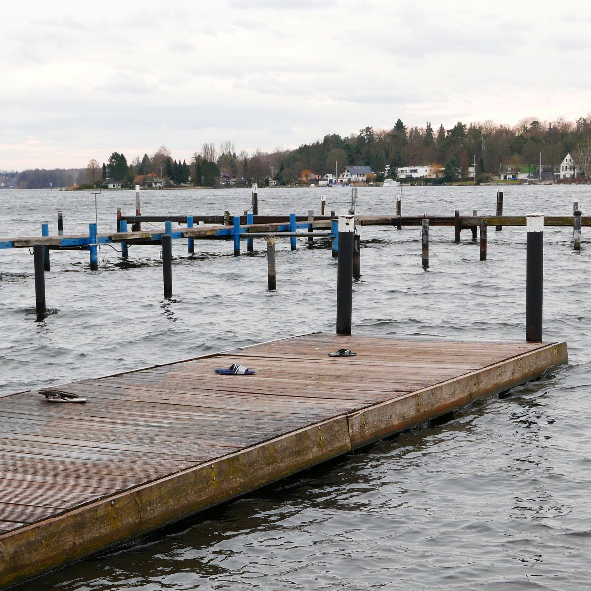 Wooden pier on choppy water, other piers visible in the background, cloudy sky.