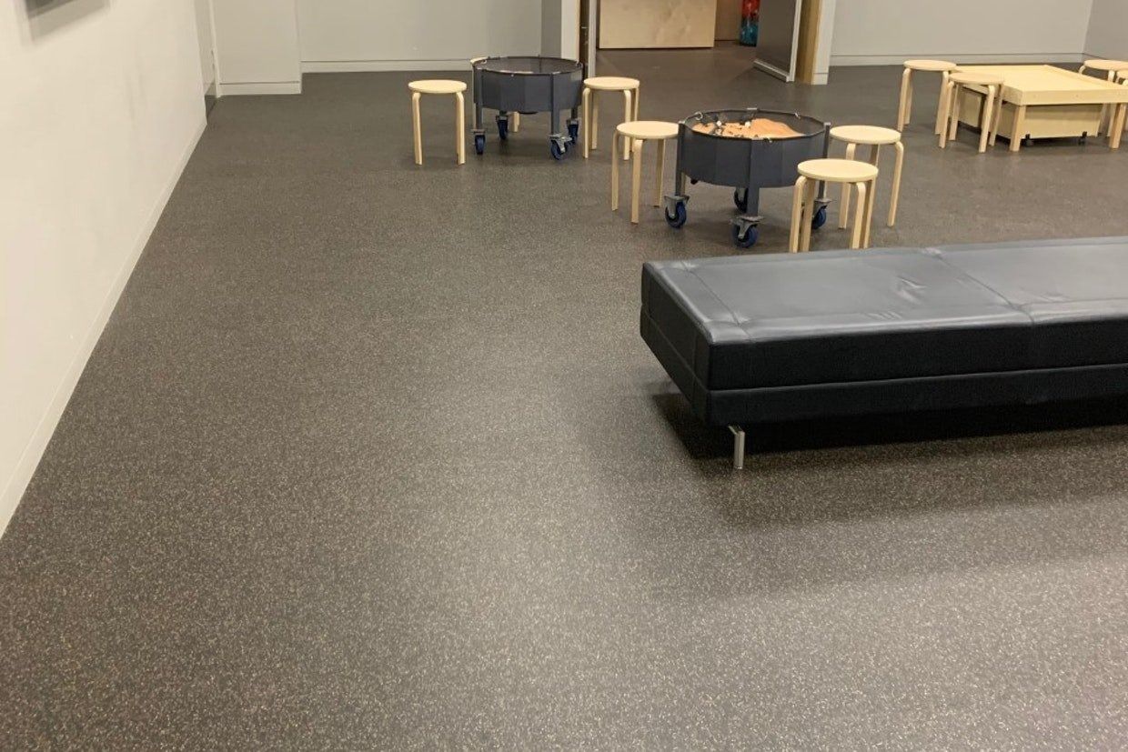 Grey Rubber Flooring in a Room With a Black Bench, Wooden Stools, and Dark Rolling Bins — Ozwide Flooring In Ciccone, NT