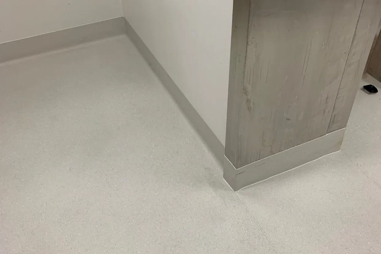 Corner of a Room With a Light Grey Floor and White Wall — Ozwide Flooring In Ciccone, NT