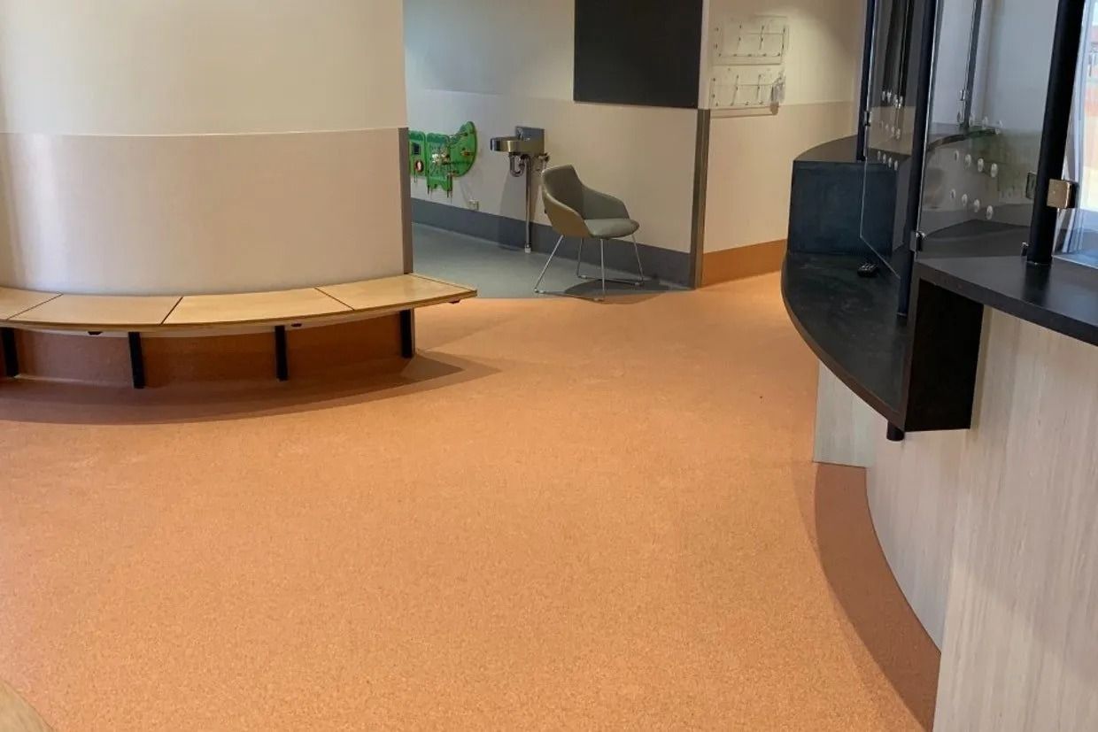 A Waiting Area With Orange Flooring, a Curved Bench, and a Reception Desk — Ozwide Flooring In Ciccone, NT