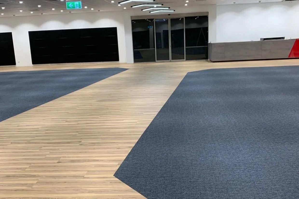 Spacious Interior With Blue Carpet, Light Wood Flooring, and Automatic Doors — Ozwide Flooring In Ciccone, NT