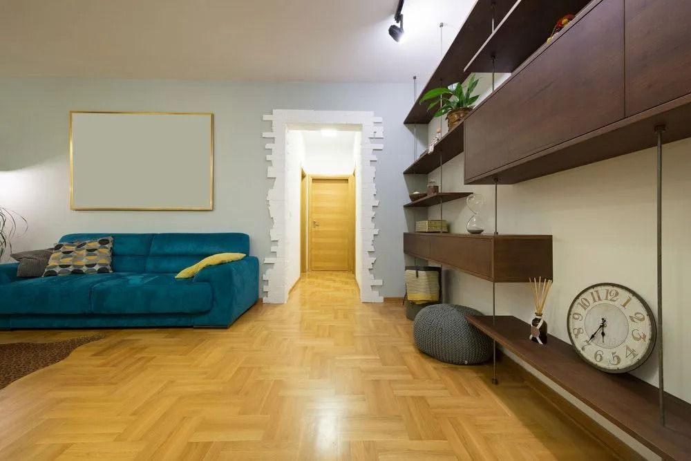 Living Room With Teal Couch, Wooden Shelves, and Light Wood Floors — Ozwide Flooring In Ciccone, NT