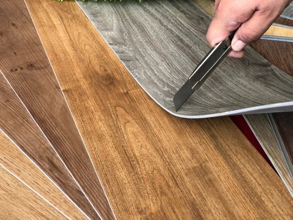 Hand Using a Utility Knife to Cut a Section of Vinyl Flooring Sample — Ozwide Flooring In Ciccone, NT