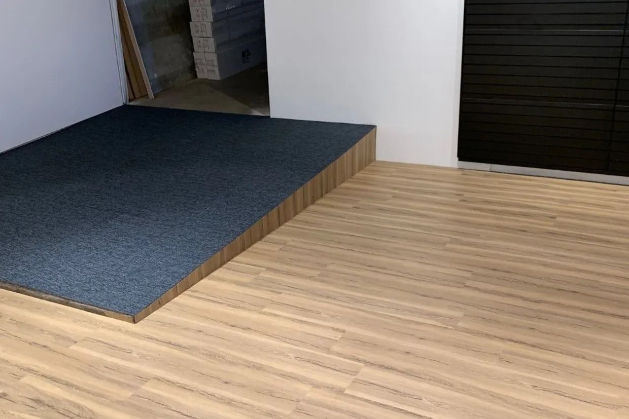 A Carpeted Platform With a Ramp in a Room With Wood Flooring, Next to a Black Door — Ozwide Flooring In Ciccone, NT