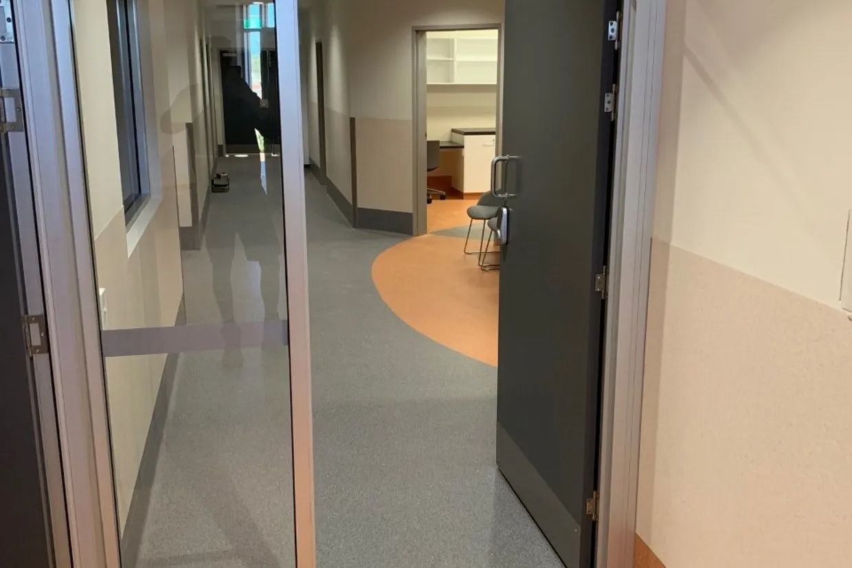 Hallway With Open Doors, Grey Flooring, Tan Walls, and a Curved Orange Floor Section — Ozwide Flooring In Ciccone, NT