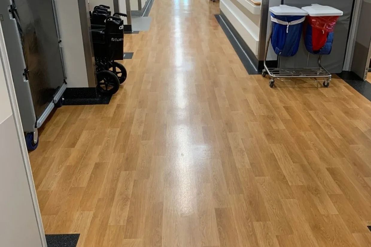 Long Hallway With Wood-look Flooring, Medical Equipment, and Waste Receptacles — Ozwide Flooring In Ciccone, NT