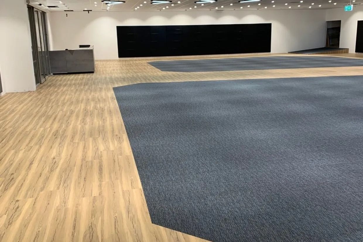 Empty Room With Wood Flooring and Blue Carpeted Area; Black Wall at Back — Ozwide Flooring In Ciccone, NT