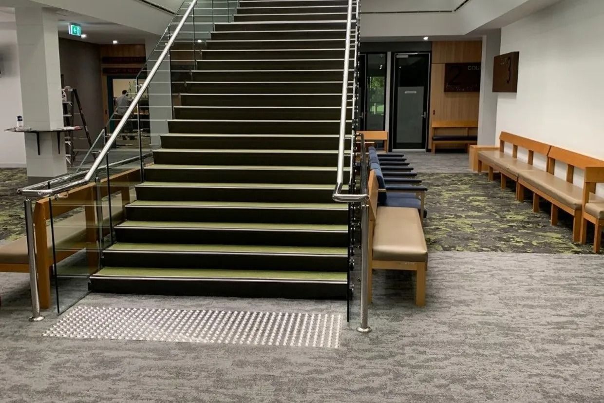 Staircase in a Building With Glass Railing and Carpeted Steps — Ozwide Flooring In Ciccone, NT