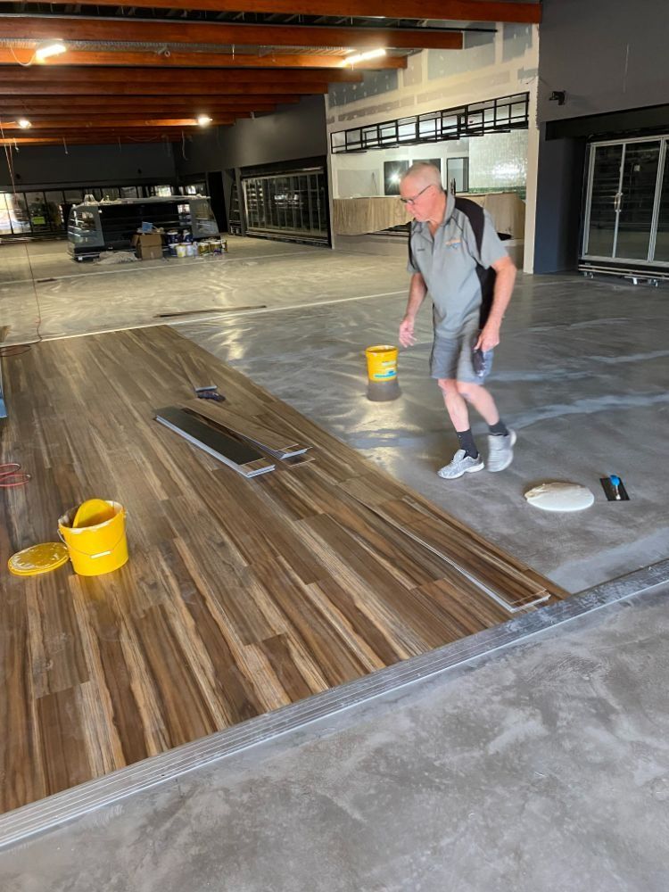 Man Installing Wood Flooring in an Open, Unfinished Commercial Space — Ozwide Flooring In Ciccone, NT