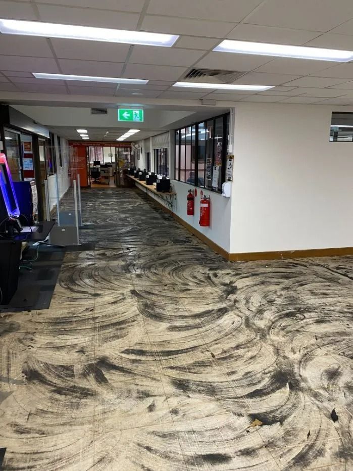 Hallway With Dark, Stained Carpet, Windows on the Right, and Exit Sign Ahead — Ozwide Flooring In Ciccone, NT