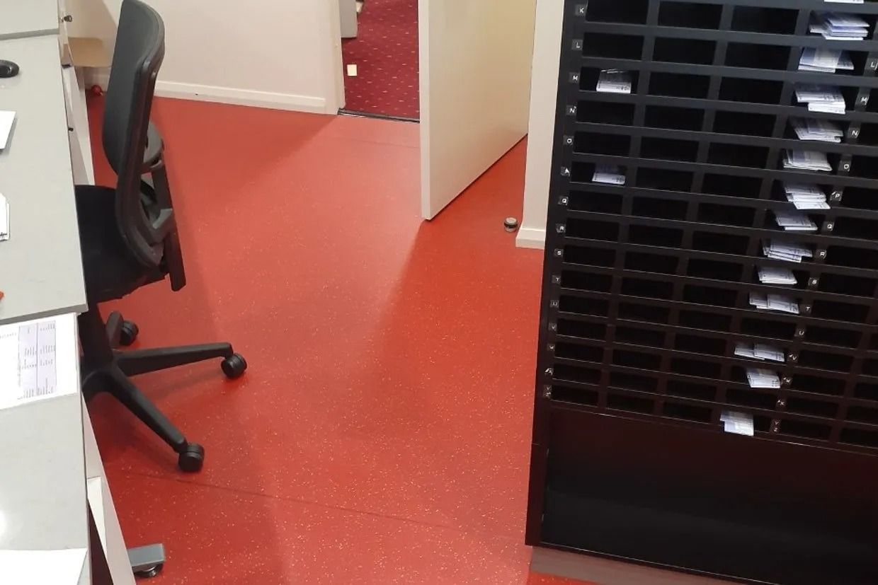 Red Floor in an Office Setting, Black Shelving Unit, Black Office Chair, and Open Doorway — Ozwide Flooring In Ciccone, NT