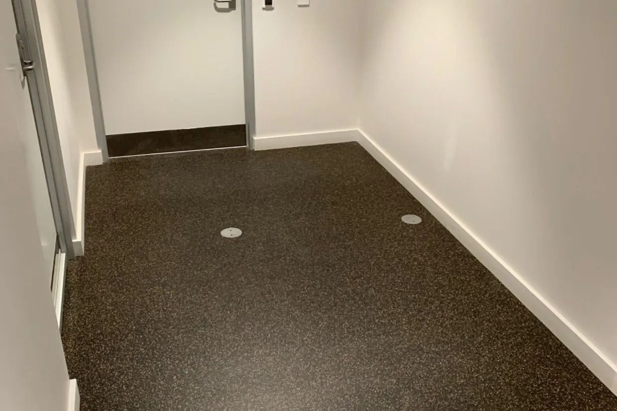 Narrow Hallway With Dark Speckled Floor, White Walls, and a Door at the End — Ozwide Flooring In Ciccone, NT