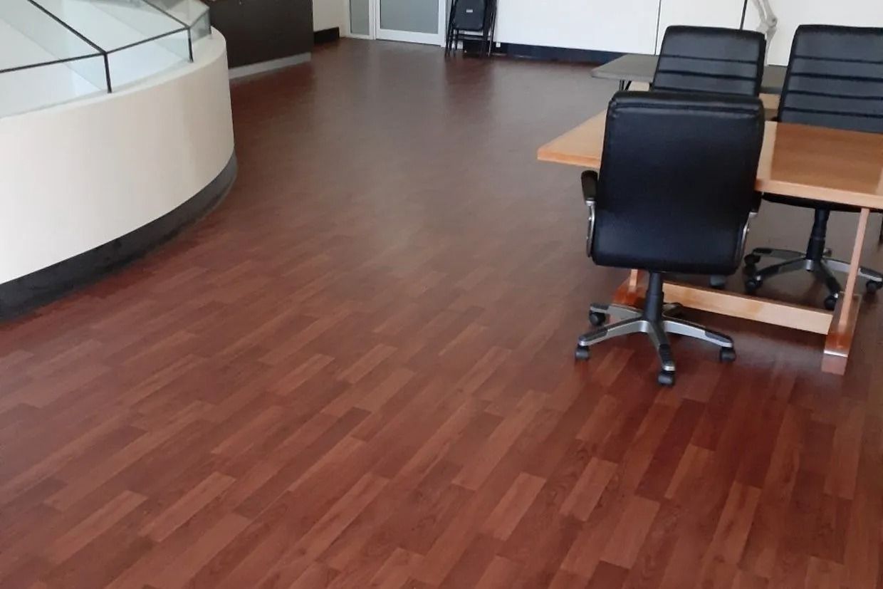 Dark Wood-look Flooring in a Room With a Curved Wall and a Table With Chairs — Ozwide Flooring In Ciccone, NT