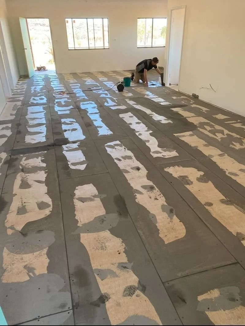 Man Applying Grey Adhesive to the Floor in a Room With White Walls — Ozwide Flooring In Alice Springs, NT