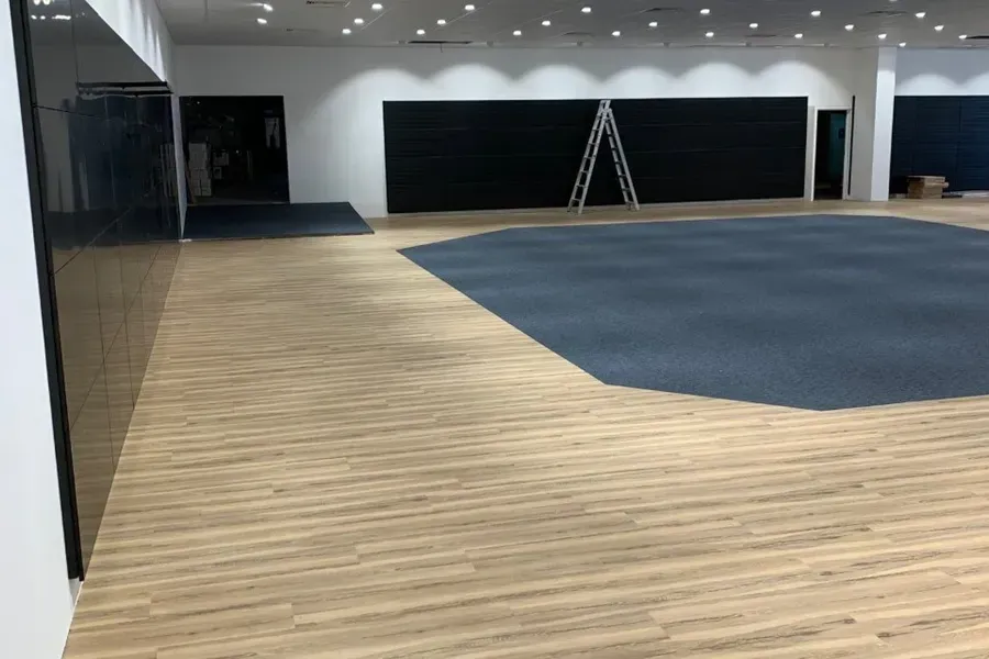 Large Room With Light Wood Flooring, a Section of Blue Carpet — Ozwide Flooring In Ciccone, NT