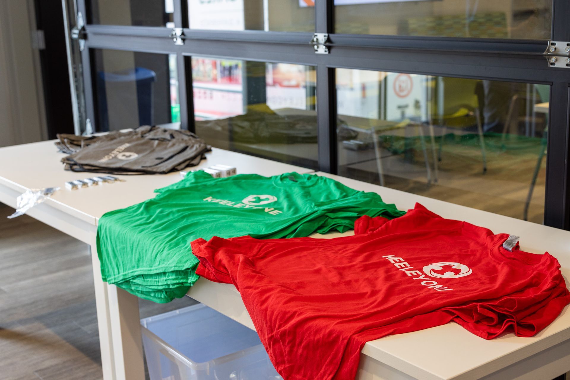 A green and a red t-shirt are sitting on a table.