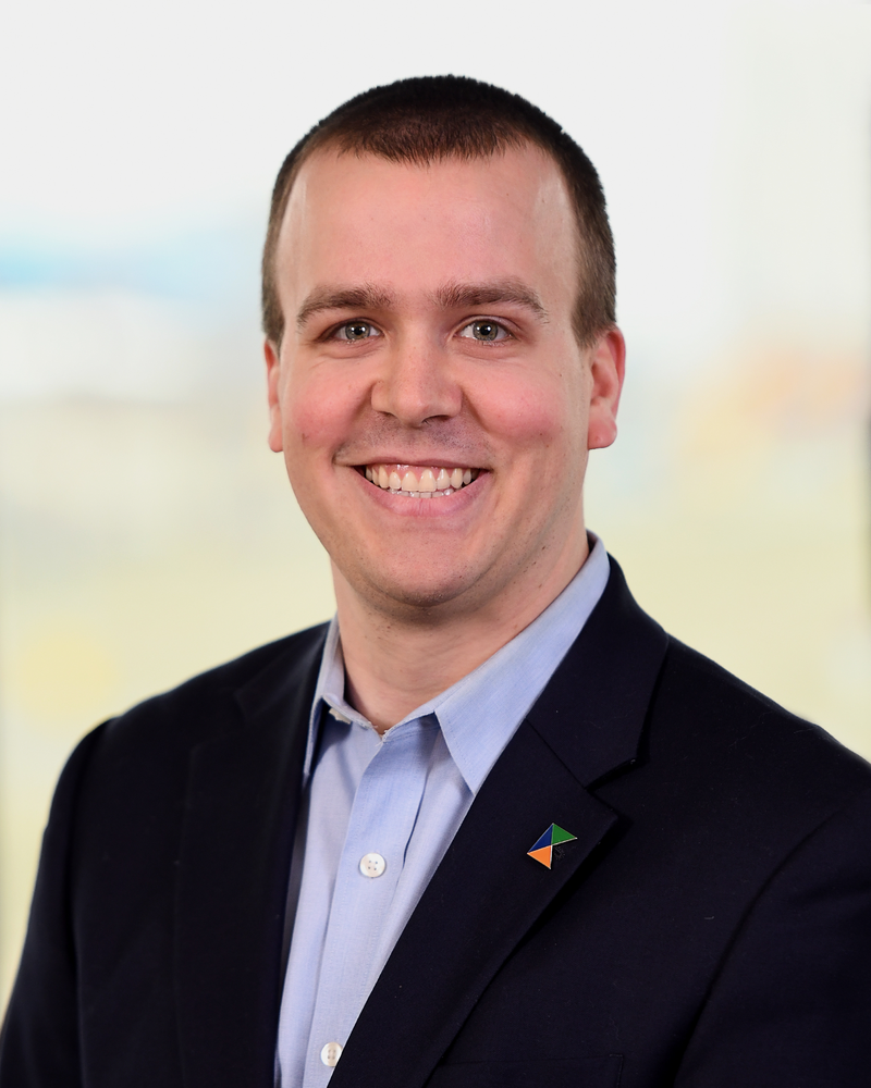 A man in a suit and blue shirt is smiling for the camera