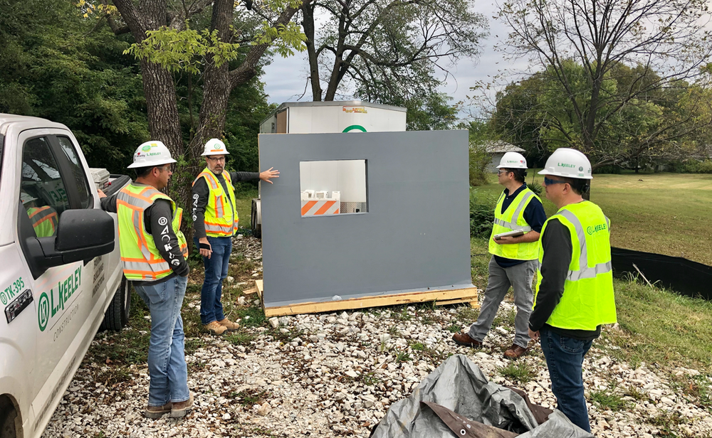 A group of construction workers are standing next to a truck.