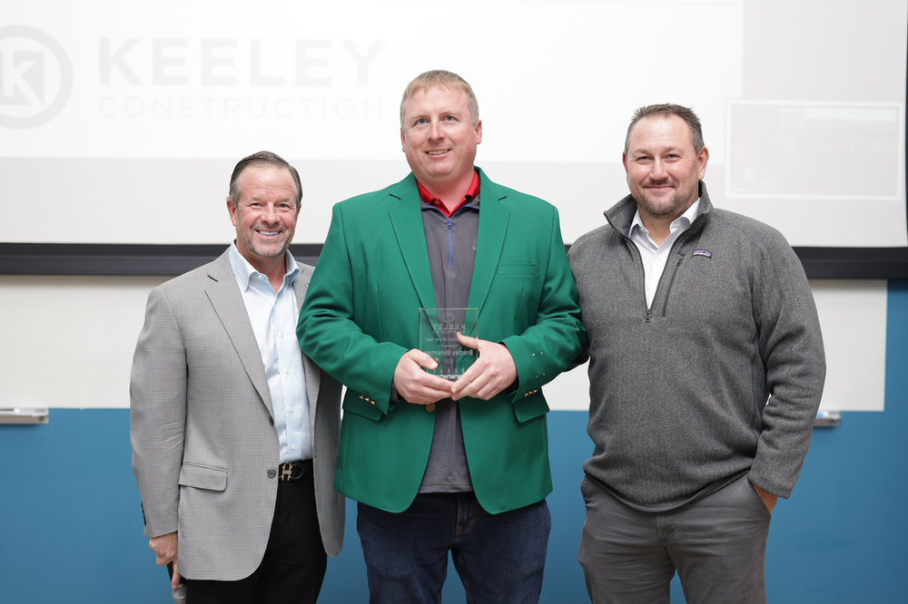 Three men are standing next to each other holding a trophy.