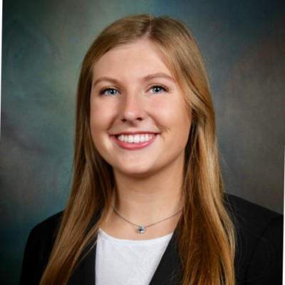 A woman wearing a white shirt and a black jacket is smiling