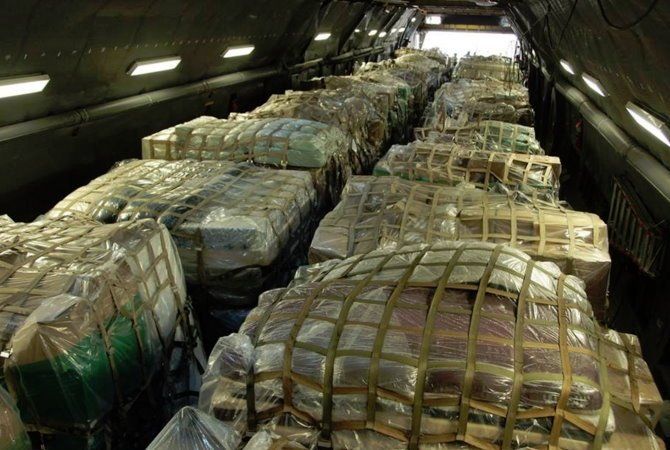 Cargo packed in a military aircraft hold, with large wrapped pallets stacked in rows