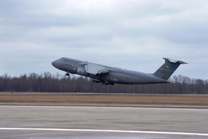 Gray cargo plane taking off from a runway under an overcast sky