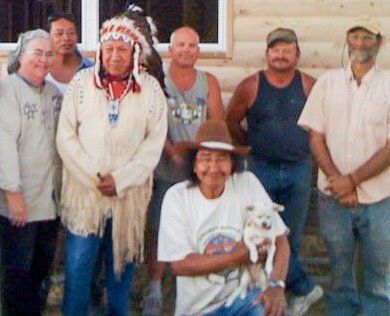 Group posing outdoors, with one person seated holding a small white dog and others standing behind.