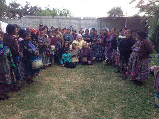 Group of people in colorful traditional clothing posing together outdoors on a grassy field