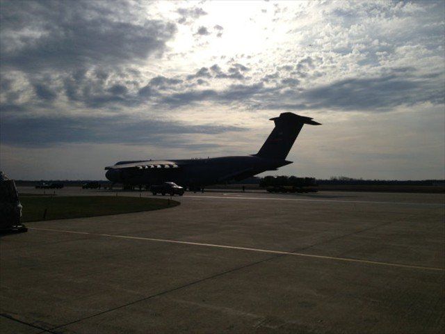 Military cargo plane on a runway under a cloudy sky at dusk