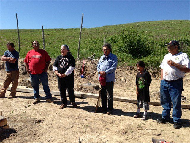 A group of people standing in the dirt in a field at Pine Ridge Reservation