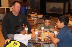 JIM Thome seated with children at a re table, eating and chatting with drinks and food on the table.