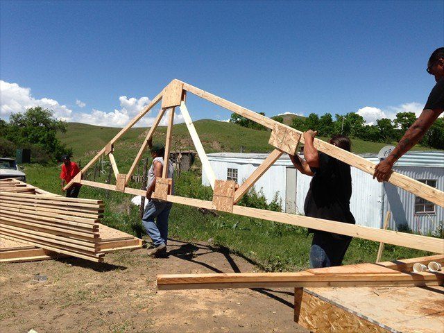 A group of people are working on a wooden structure at Pine Ridge Reservation