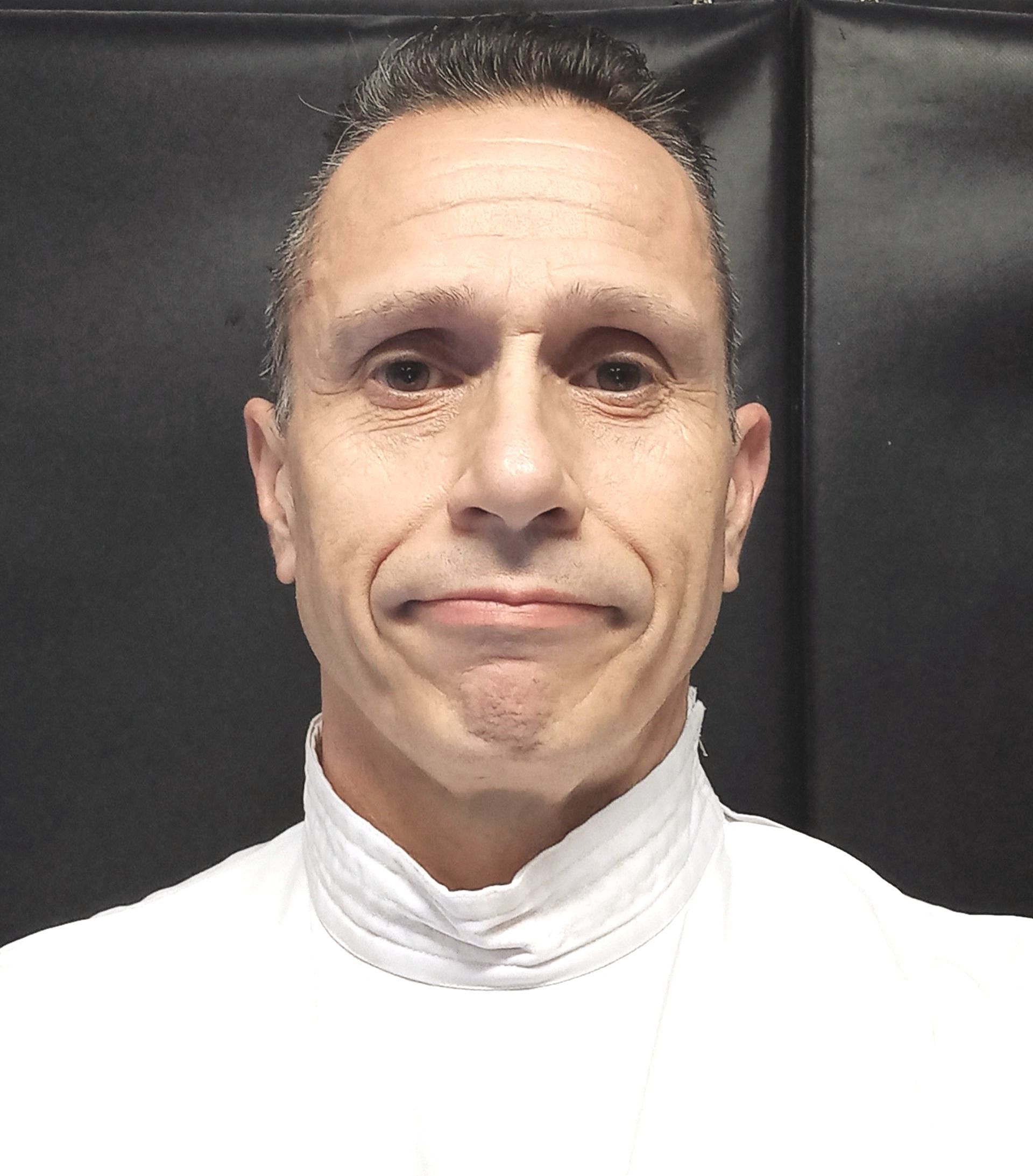 A man in a white shirt is smiling for the camera