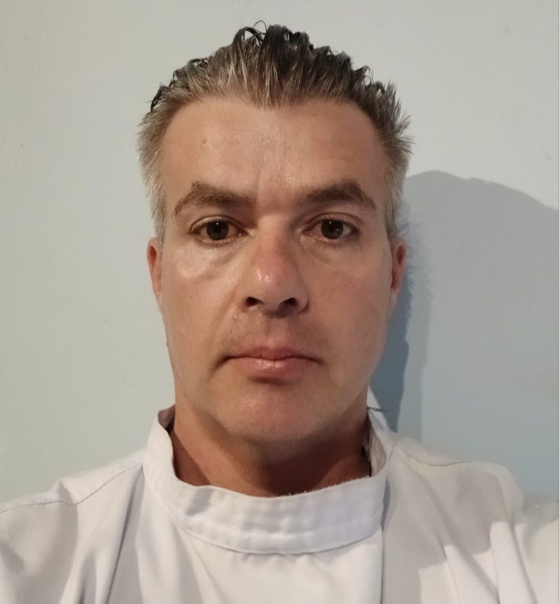 A man in a white coat is taking a selfie
