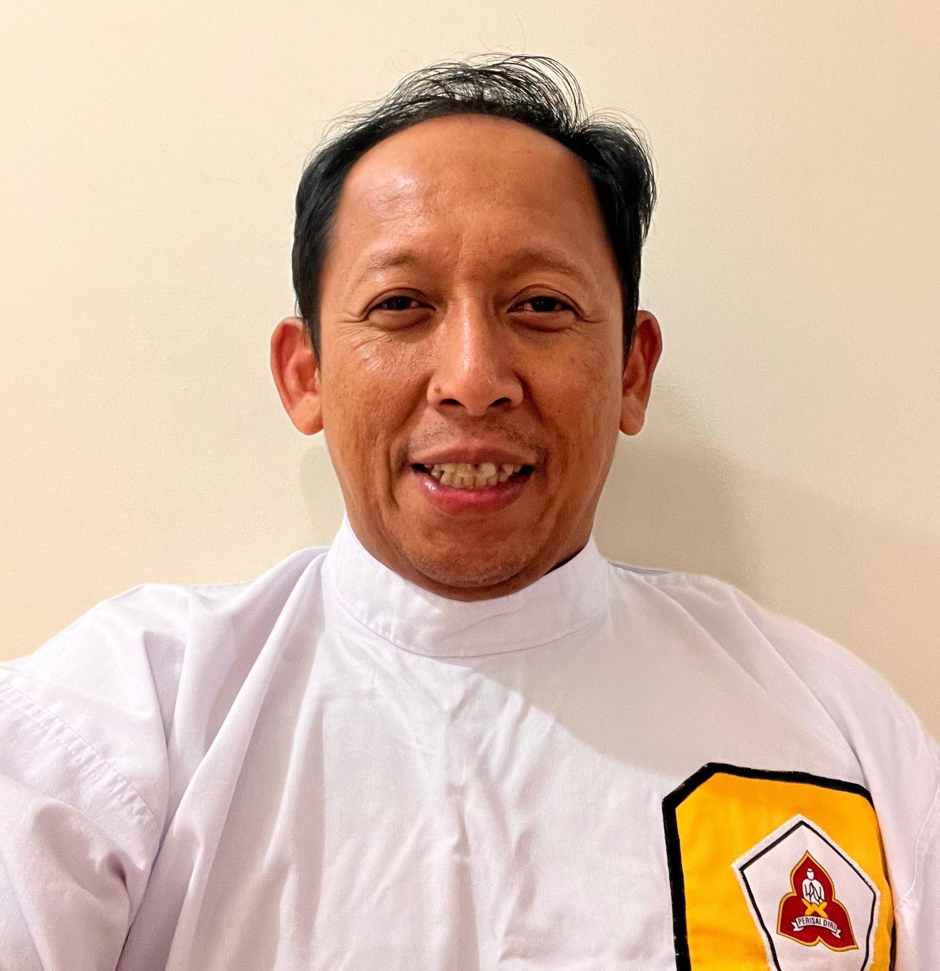 A man wearing a white shirt with an a on the pocket