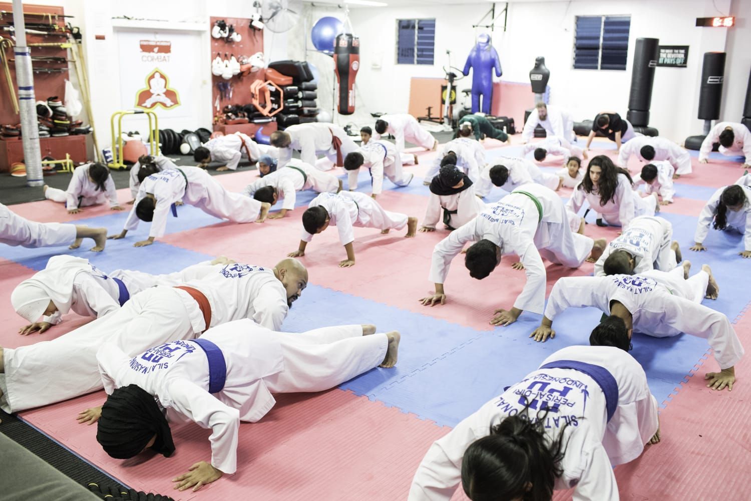 A group of people are doing push ups in a gym.