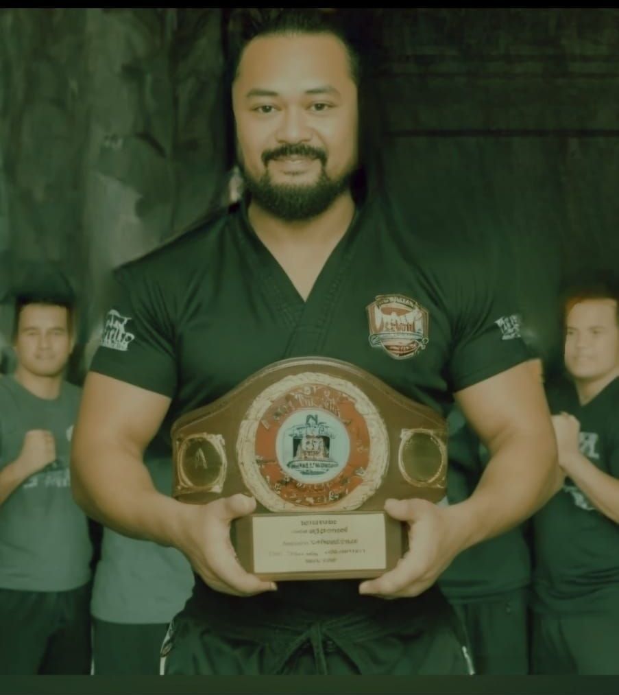 A man in a black shirt is holding a plaque that says karate