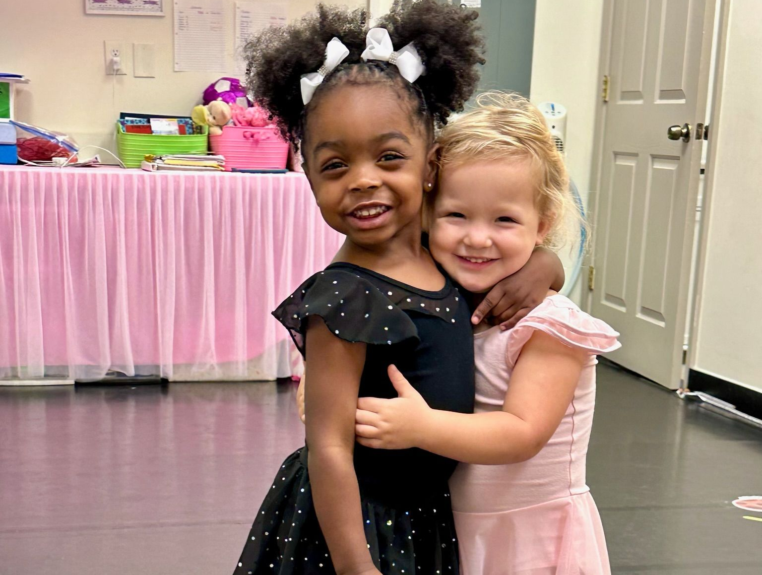 Two dancers from the pre-school and kindergarten classes hugging