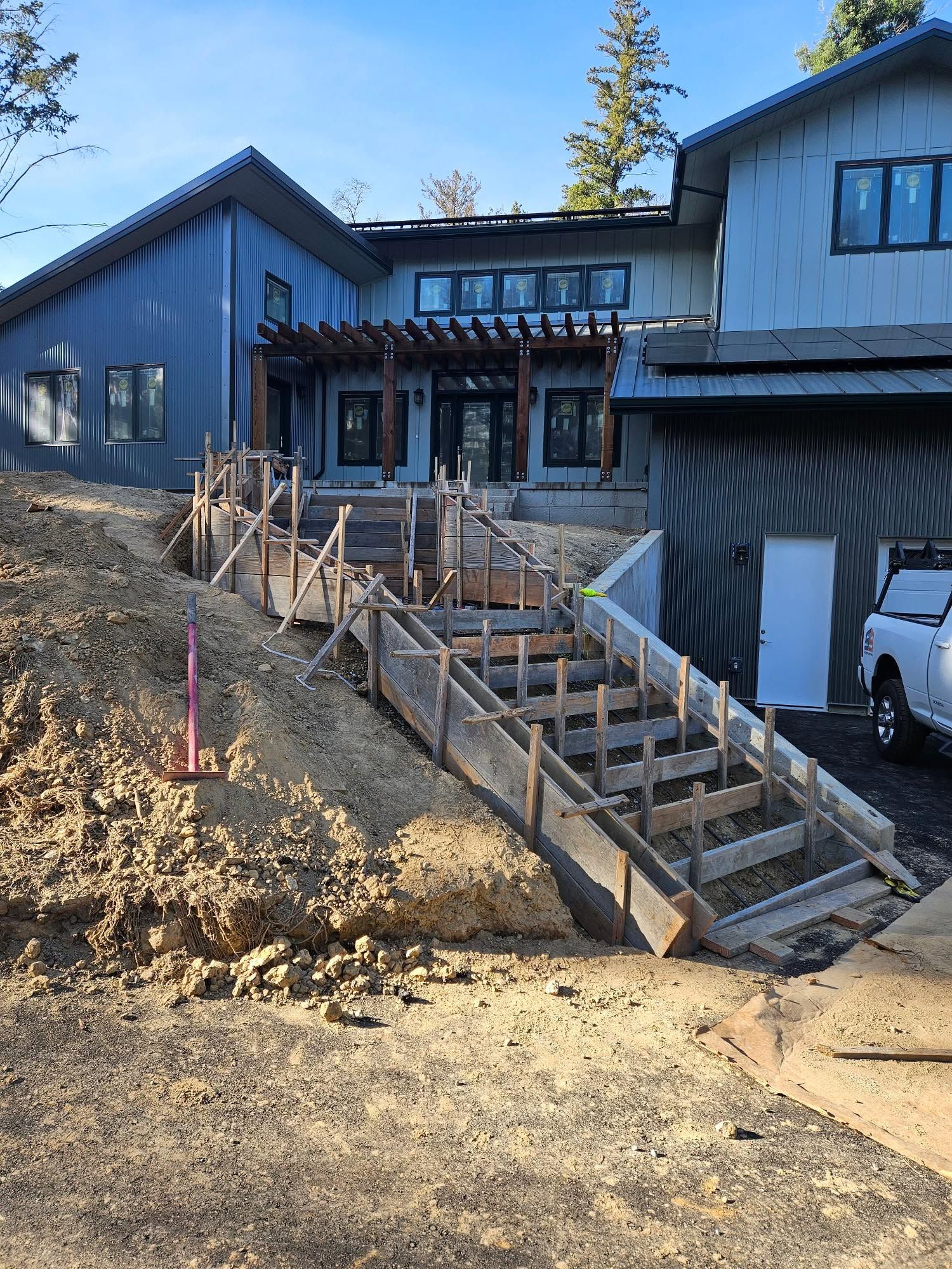Front of a blue house with a wooden staircase and railing leading up from a dirt yard.