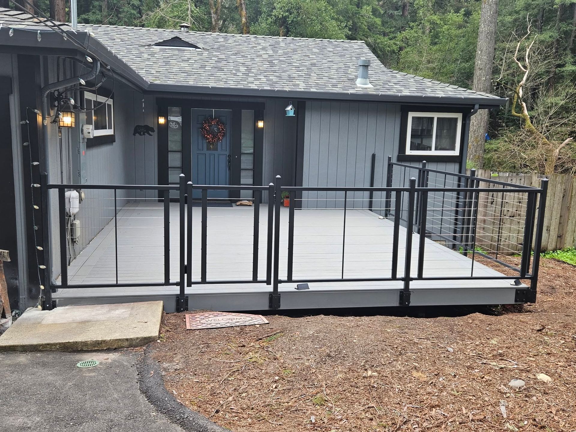 Gray house with black railings and a wide wheelchair-accessible ramp leading to the front door.