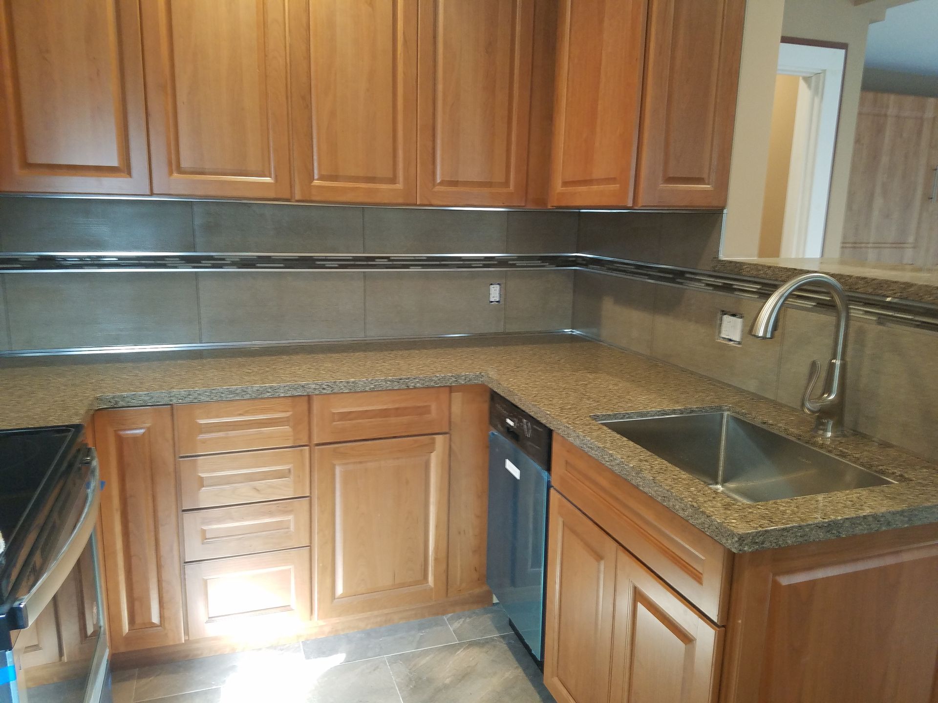 Wooden kitchen with granite countertops, sink, and dishwasher under upper cabinets