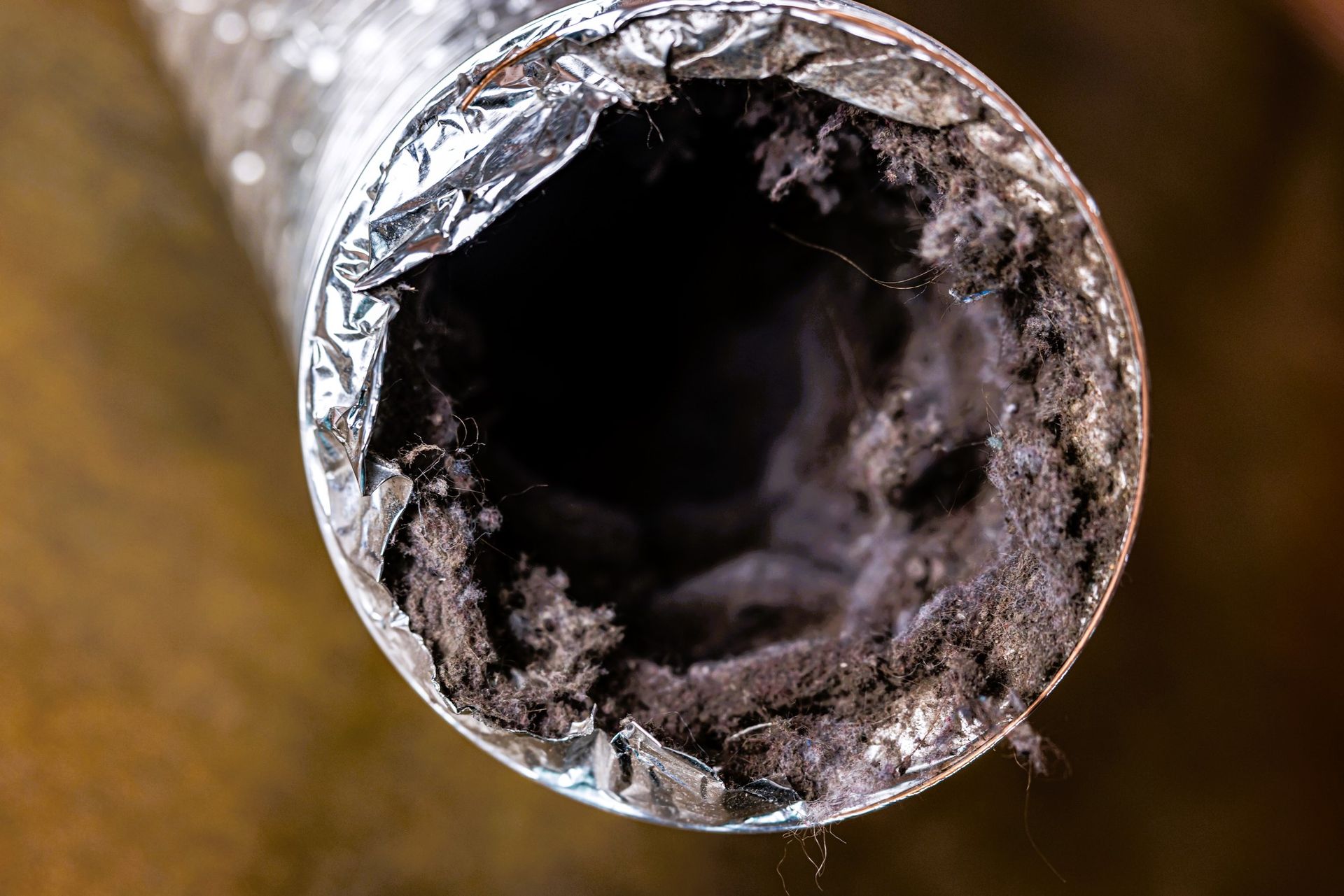 A flexible aluminum dryer vent duct clogged with lint, dust, and dirt